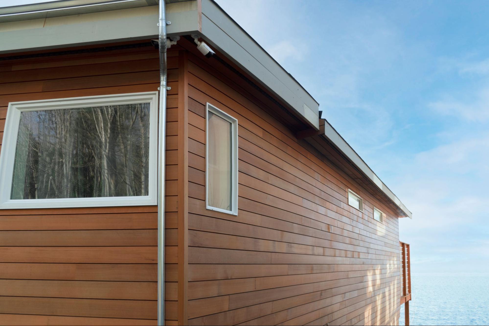 Corner view of a beach house with wood siding under a clear blue sky.