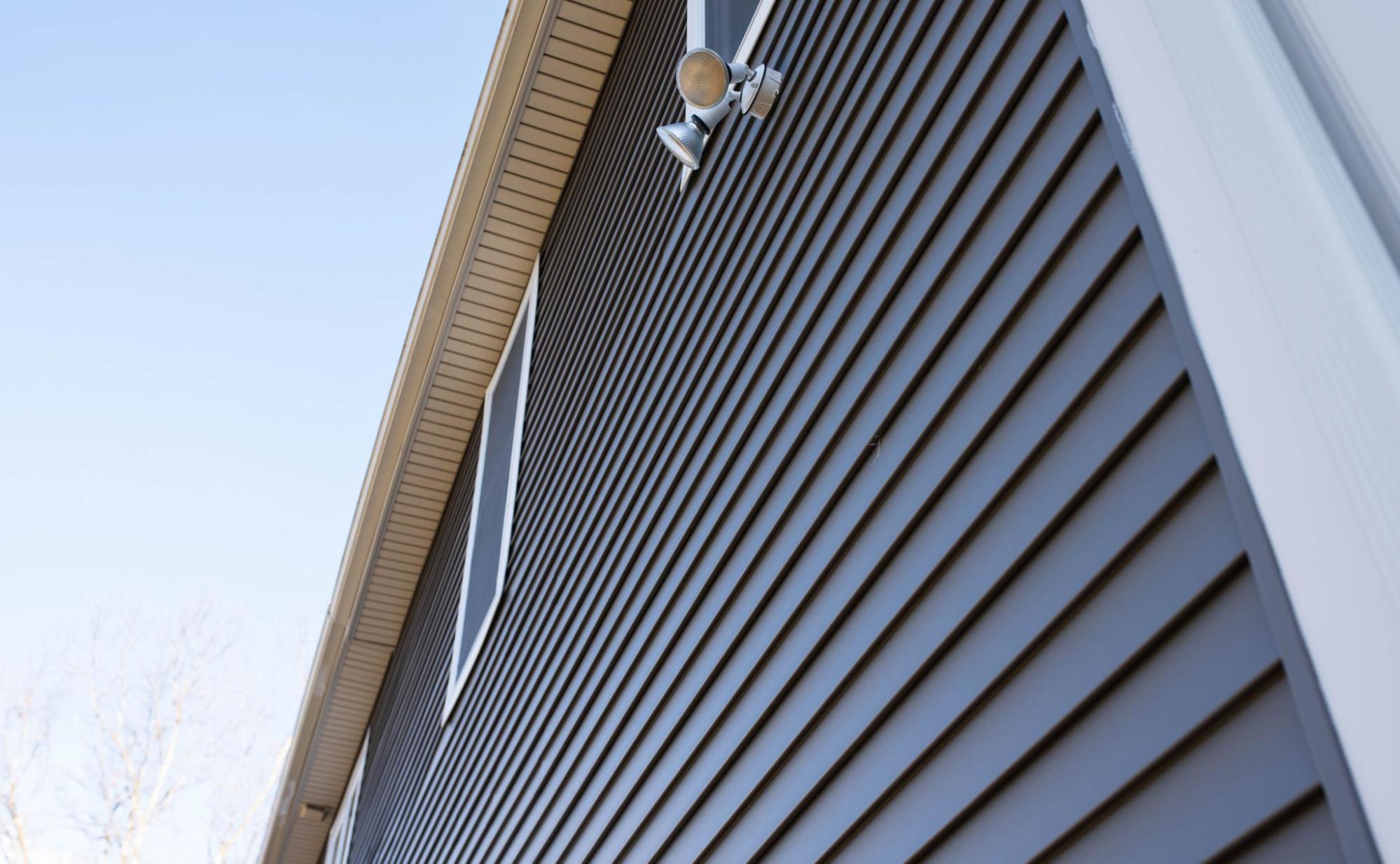 Upward view of a home exterior with newly replaced vinyl siding panels