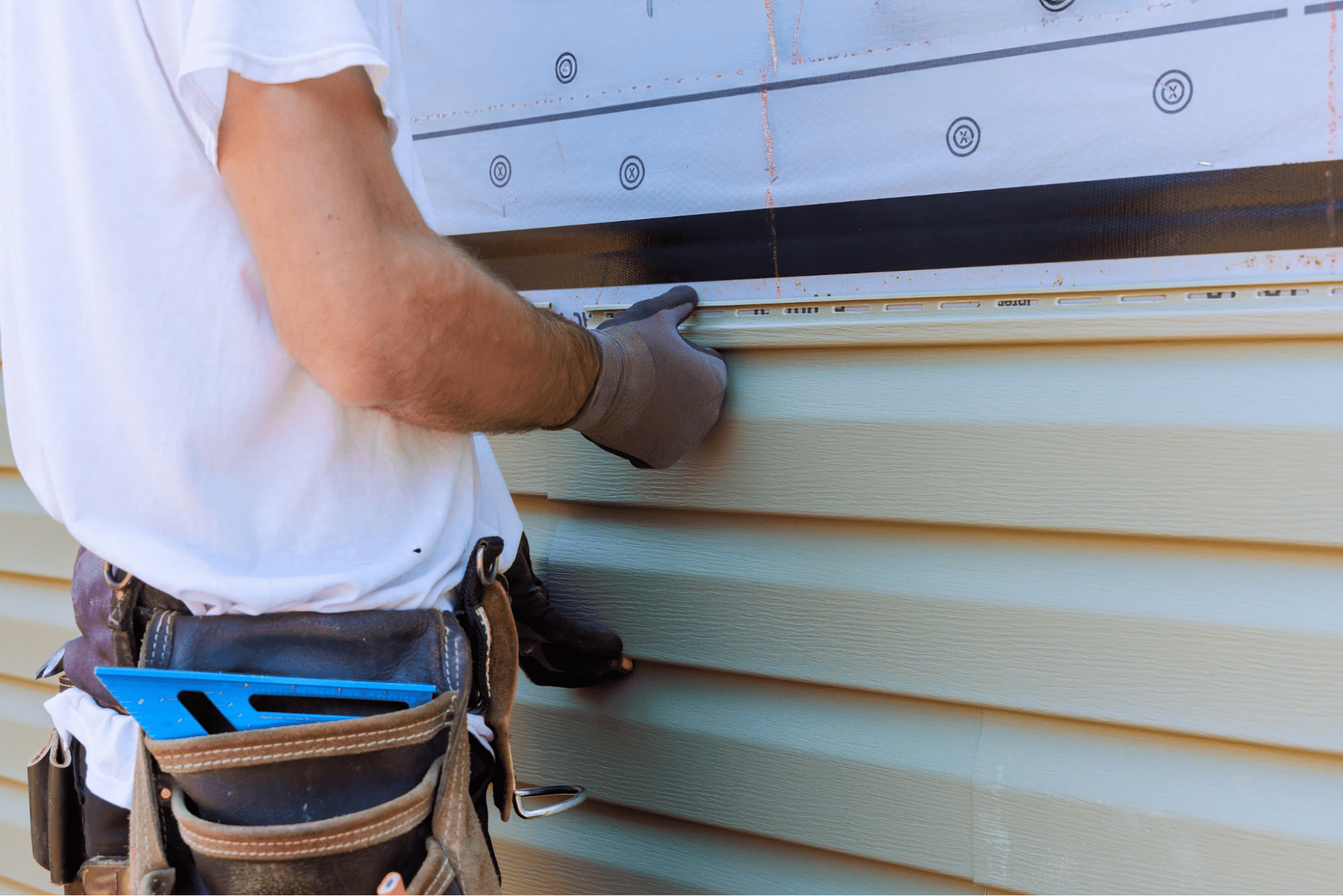 A contractor installing vinyl siding.