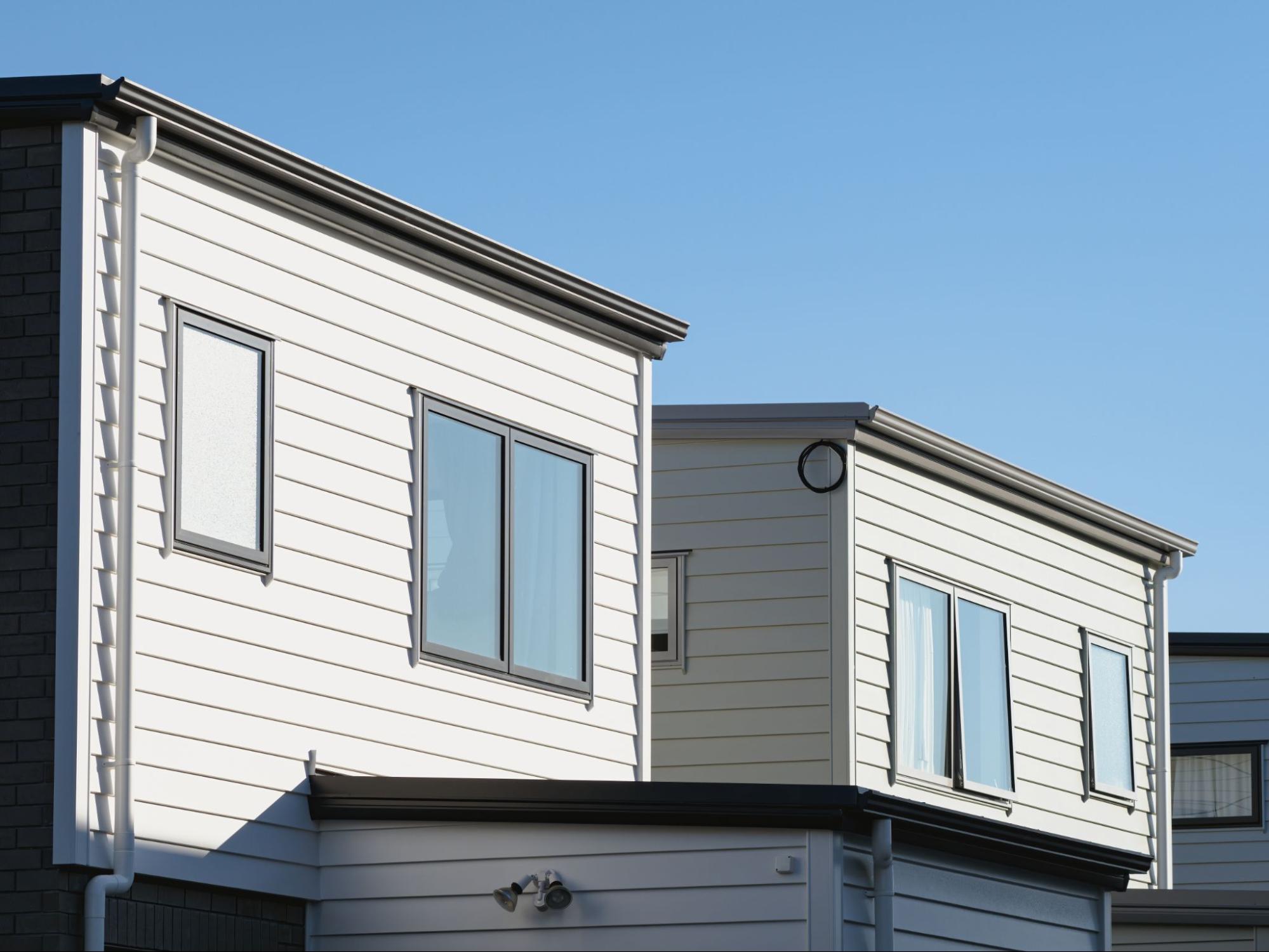 Two residential townhouses featuring clean, white vinyl siding exteriors.