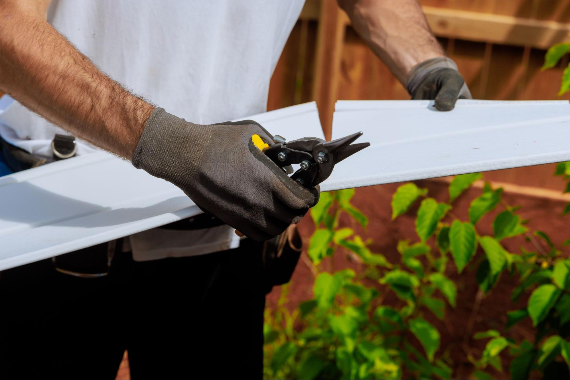 A skilled craftsman measures and cuts a vinyl siding panel to fit before installation.