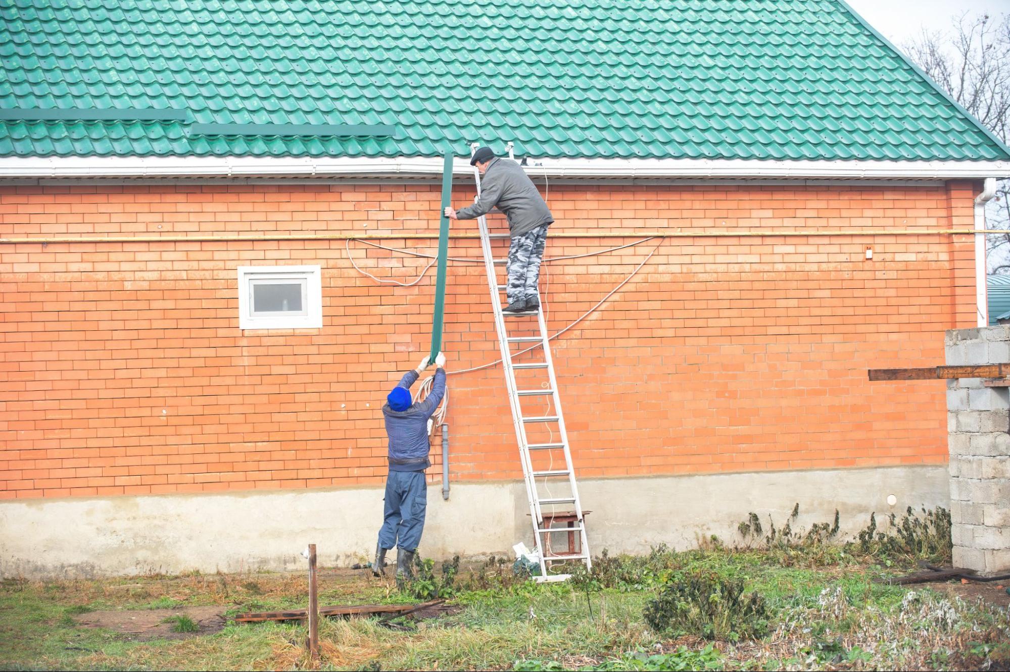 Crew installs snow guards to support clean gutters and prevent winter ice buildup on the roof and drainage system.