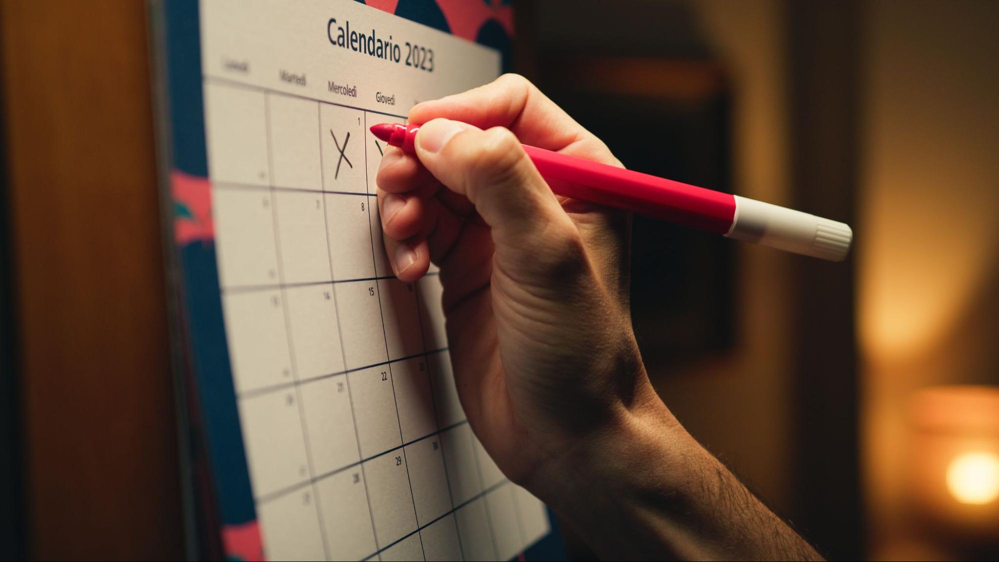 Hand marking a calendar date with a red marker to schedule a roof replacement.