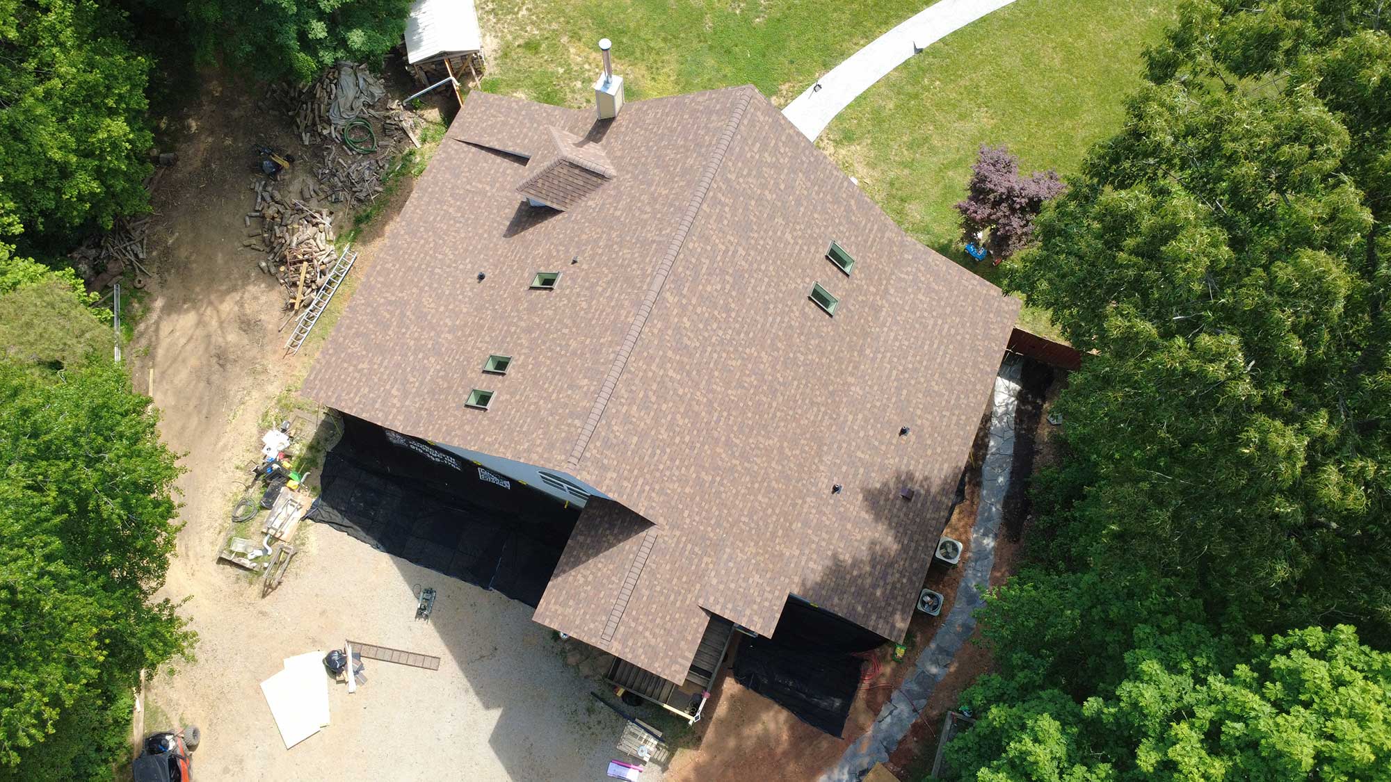 Aerial shot of a house highlighting its roof structure and surrounding area.