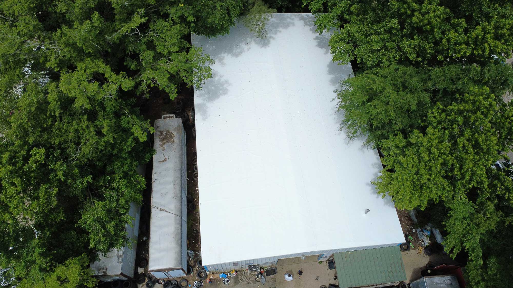 Aerial view of a white building surrounded by green trees, showcasing the harmonious blend of architecture and nature.