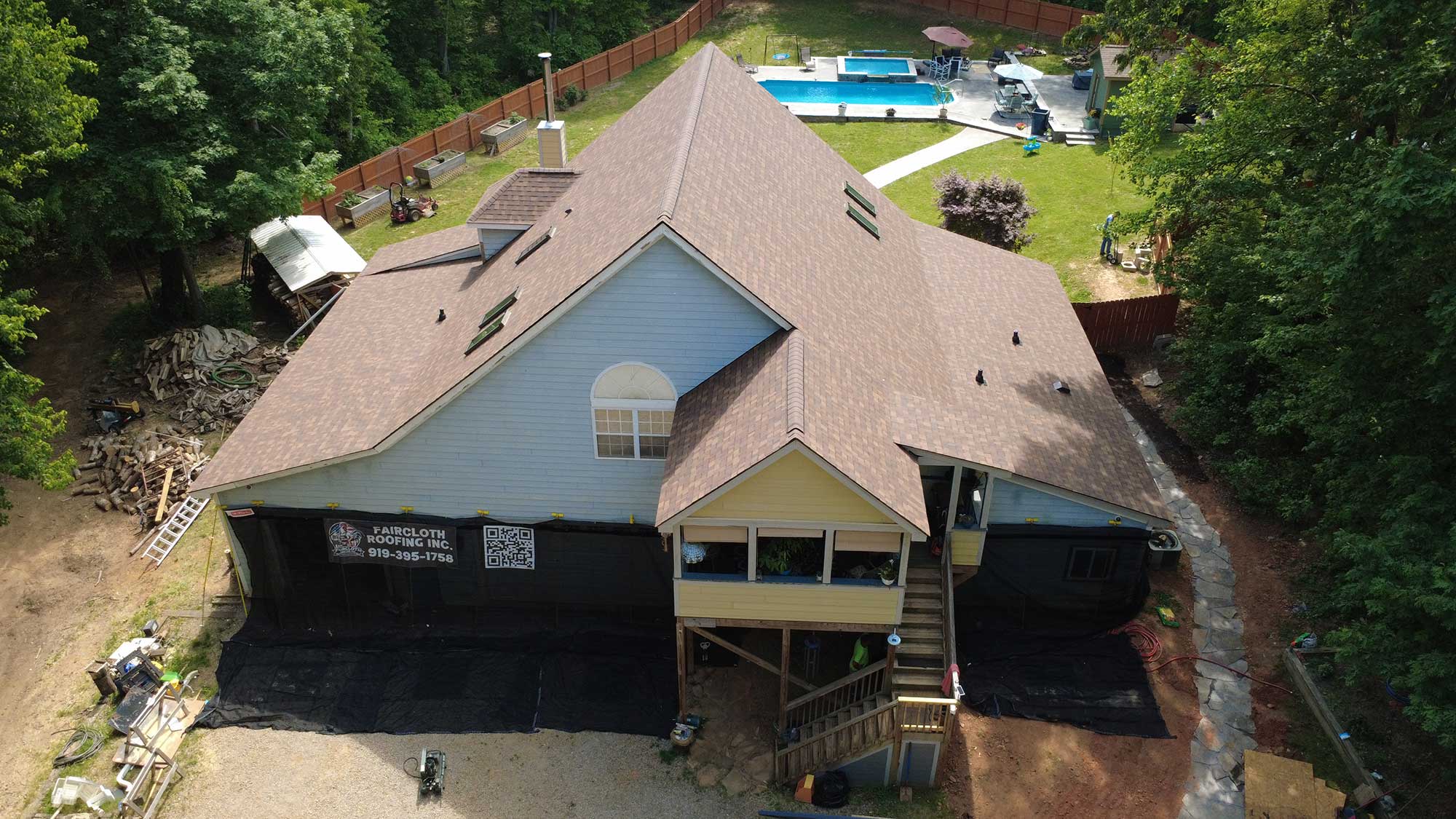 Bird's-eye view of a residential house featuring its roof and adjacent yard.