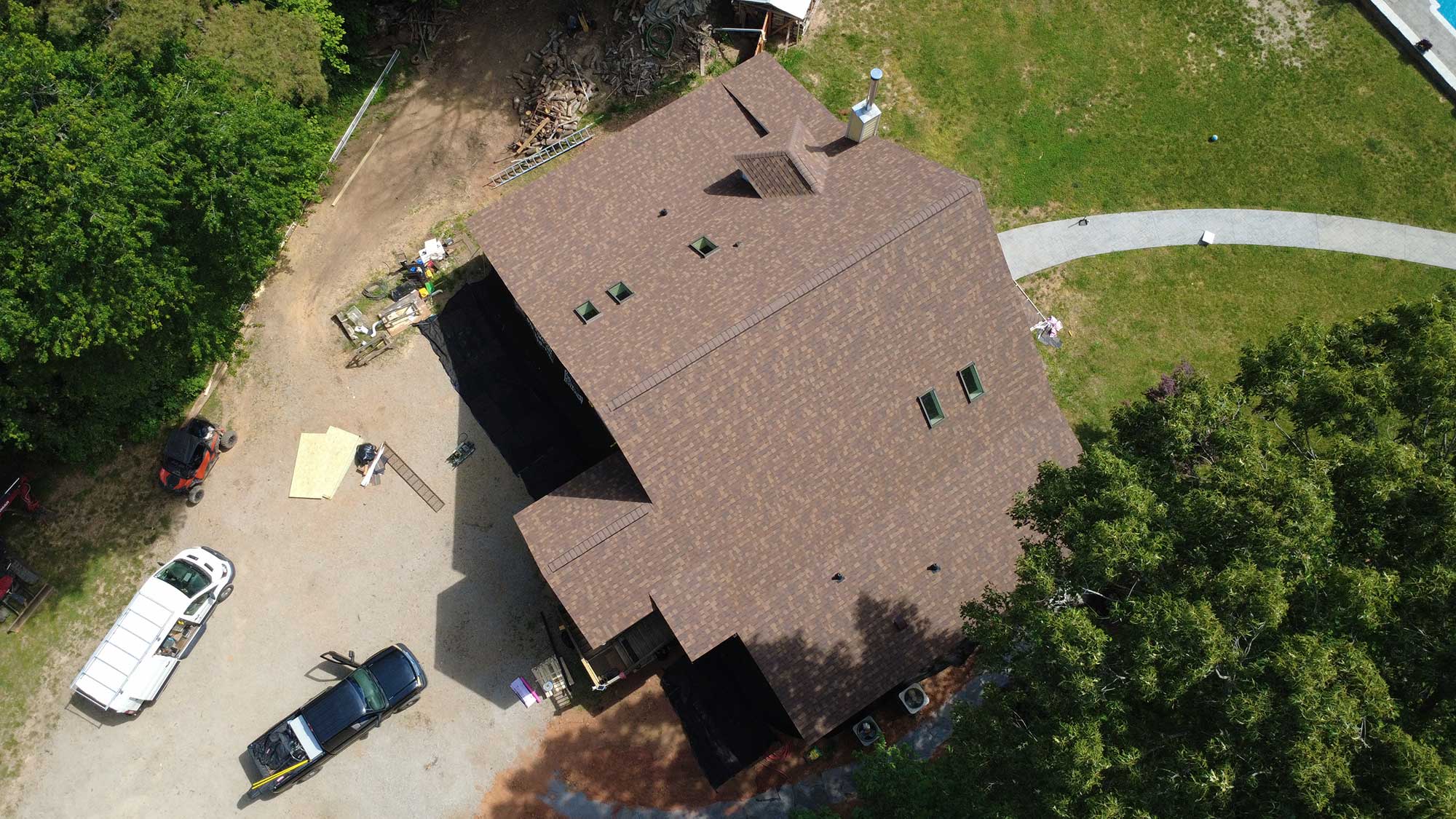 Bird's-eye view of a residential house featuring its roof and nearby trees.