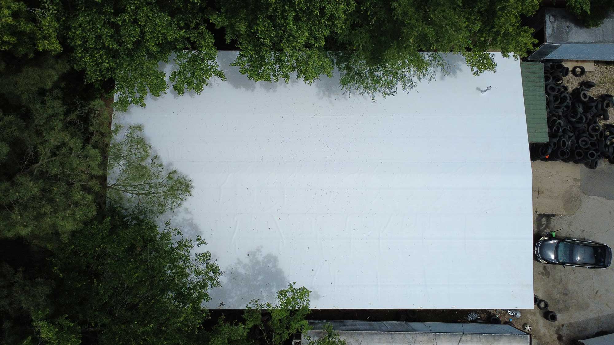 Overhead view of a white building nestled among lush trees, illustrating a peaceful natural setting