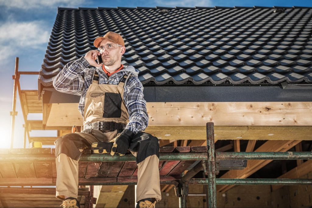 A roof specialist on the roof answers a call.