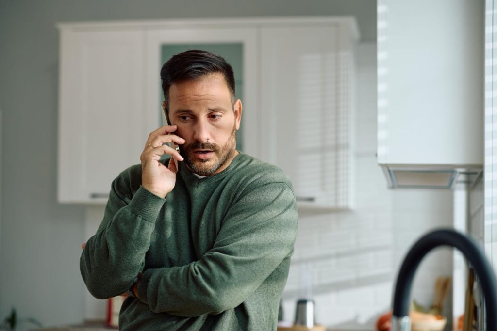 Man on the phone in a kitchen.